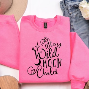 May include: A pink sweatshirt with black text that reads "Stay Wild Moon Child".