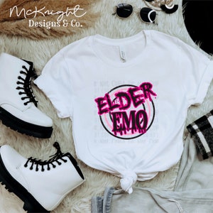 May include: White t-shirt with a black circle and pink text that says "Elder Emo".