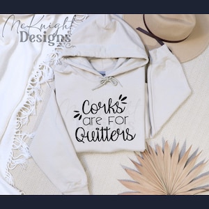 May include: A beige hoodie with a black graphic that says "Corks are for Quitters".