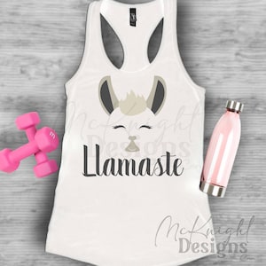 Op de afbeelding: Een wit tanktop met een lama-gezichtsgrafiek en de tekst "Llamaste" gedrukt op de voorkant.