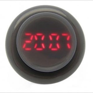 May include: A black round button with a red digital display showing the number 2017.
