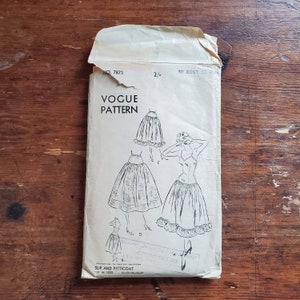 Op de afbeelding: Vintage Vogue naaipatroon voor een slip en een petticoat. Het patroon is voor maten 30 buste en 33 heupen. Het patroon toont drie verschillende stijlen van slips en petticoats, allemaal met kantversiering.