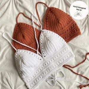 May include: Two crochet halter tops, one in white and one in rust orange, featuring triangular cups with textured stitch patterns and thin adjustable tie straps. A circular white label in the corner displays the text Hand-Designed Not AI.