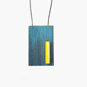 Collier pendentif en bois coloré peint à la main en gris et pétrole avec des détails jaunes.