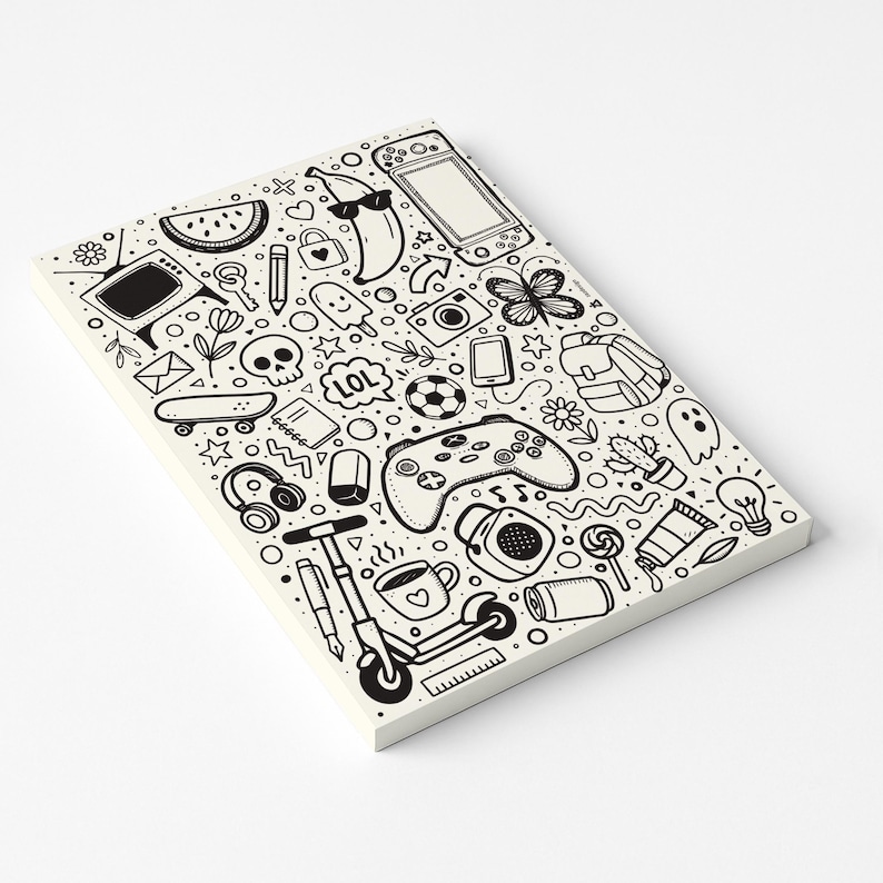 May include: A white notepad with a black doodle design featuring a variety of illustrations. The drawings include a banana wearing sunglasses, a video game controller, a skull, and a skateboard.