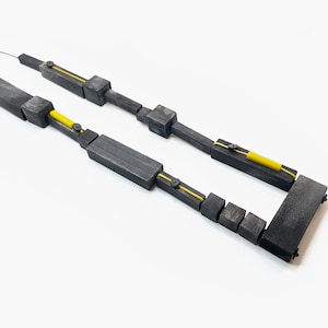 May include: A black and yellow geometric necklace made of wood. The necklace is made up of rectangular and square shapes that are connected together with small metal pieces. The necklace is about 18 inches long.