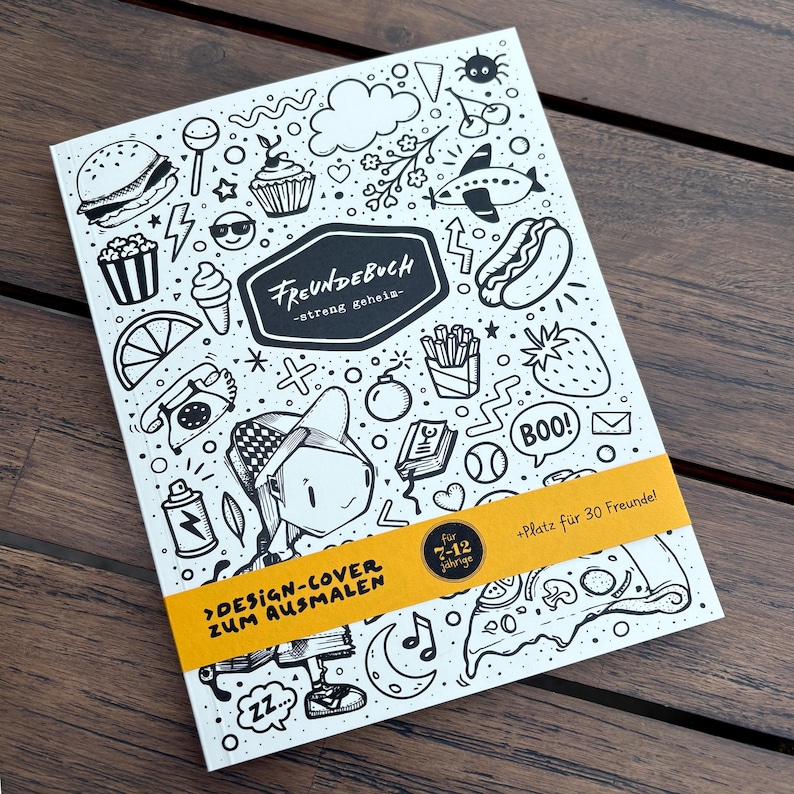May include: A white activity book with black line art illustrations of food, objects, and a cartoon figure. The book has the text "FREUNDEBUCH" and "DESIGN-COVER ZUM AUSMALEN" with a yellow band that reads "f&uuml;r 7-12 J&auml;hrige" and "+Platz f&uuml;r 30 Freunde!"