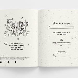 May include: Open notebook with a cream-colored speckled paper. The left page has the words "FREUNDE SIND WIE STERNE" in a decorative font, with star illustrations. The right page has text in German.