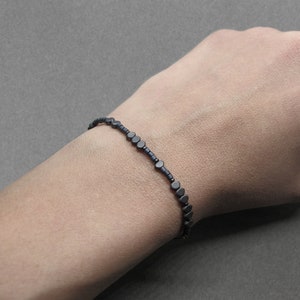 May include: A black beaded bracelet with small, round beads.
