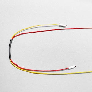 Adjustable cord necklace with red and yellow waxed cords, minimalist geometric jewelry closure detail, modern Bauhaus inspired necklace design, contemporary handmade statement necklace on neutral light background, colorful avant garde jewelry close-up