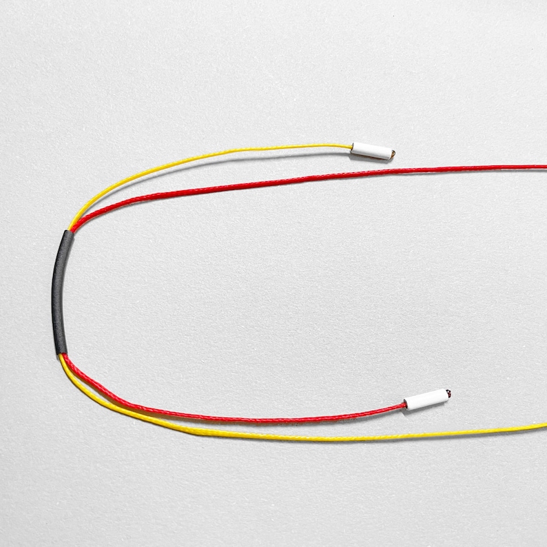 Adjustable cord necklace with red and yellow waxed cords, minimalist geometric jewelry closure detail, modern Bauhaus inspired necklace design, contemporary handmade statement necklace on neutral light background, colorful avant garde jewelry close-up