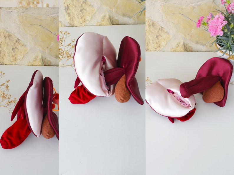 May include: A plush toy shaped like a heart with a burgundy exterior and a pink interior. The heart is open and the interior is visible. The toy is made of soft fabric and has a three-dimensional shape.