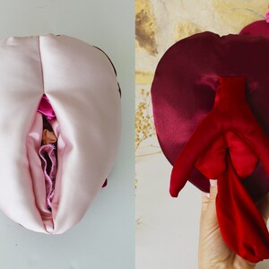 May include: Two heart-shaped pillows, one pink and one burgundy, with a red satin interior. The pillows are sewn together to create a unique shape.