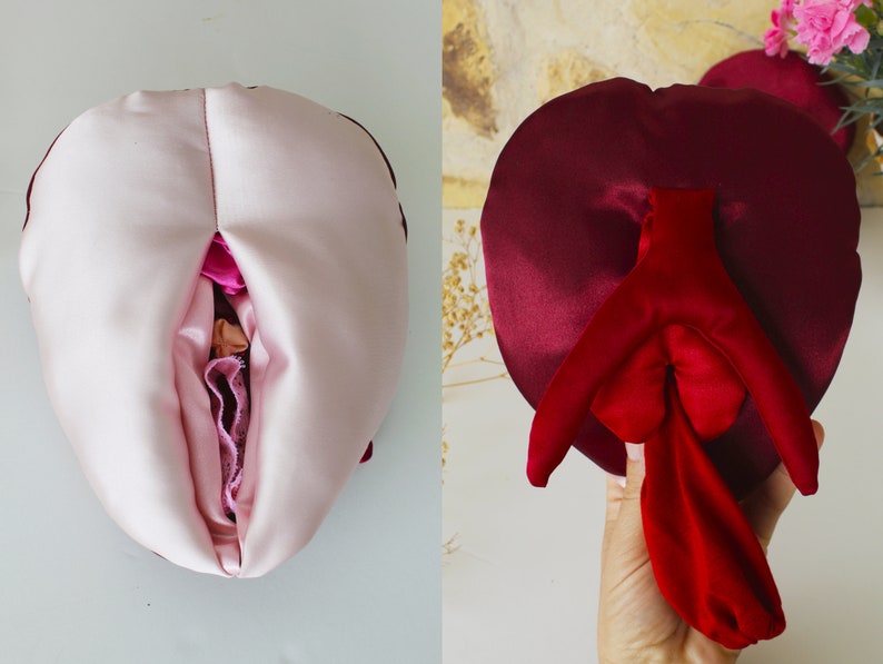 May include: Two heart-shaped pillows, one pink and one burgundy, with a red satin interior. The pillows are sewn together to create a unique shape.
