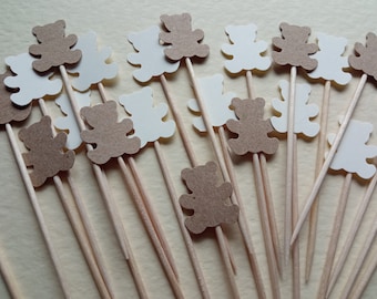May include: A collection of brown and white teddy bear cutouts on wooden skewers. The bears are arranged in a random pattern.