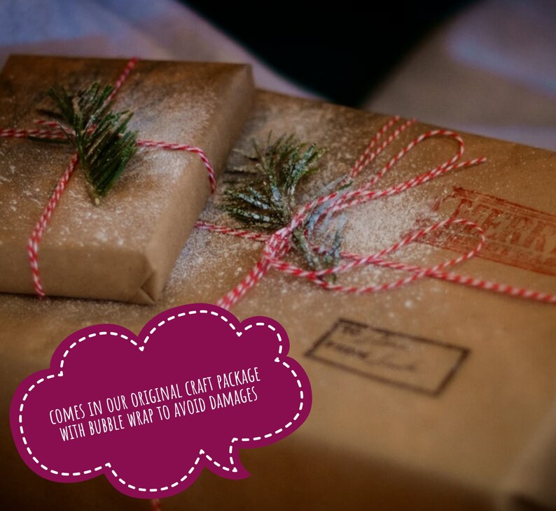 May include: Two rectangular packages wrapped in brown craft paper, tied with red and white baker's twine, and decorated with small green pine sprigs. The packages are dusted with white powder and feature a red ink stamp and a shipping label.