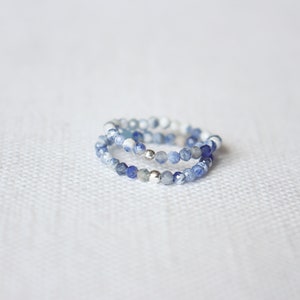 Peut inclure: Trois bagues empilées en perles de pierres précieuses bleues et blanches avec des accents argentés.