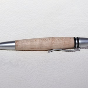 Könnte beinhalten: Ein silberner und hölzerner Stift mit einem schwarzen Band in der Nähe der Spitze. Der Stift hat einen Clip an der Seite.