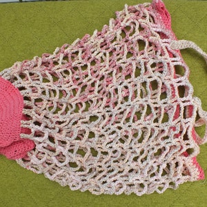 May include: A pink and white crocheted mesh bag with a pink crocheted handle. The bag is made of a soft, lightweight material and has a delicate, airy design.
