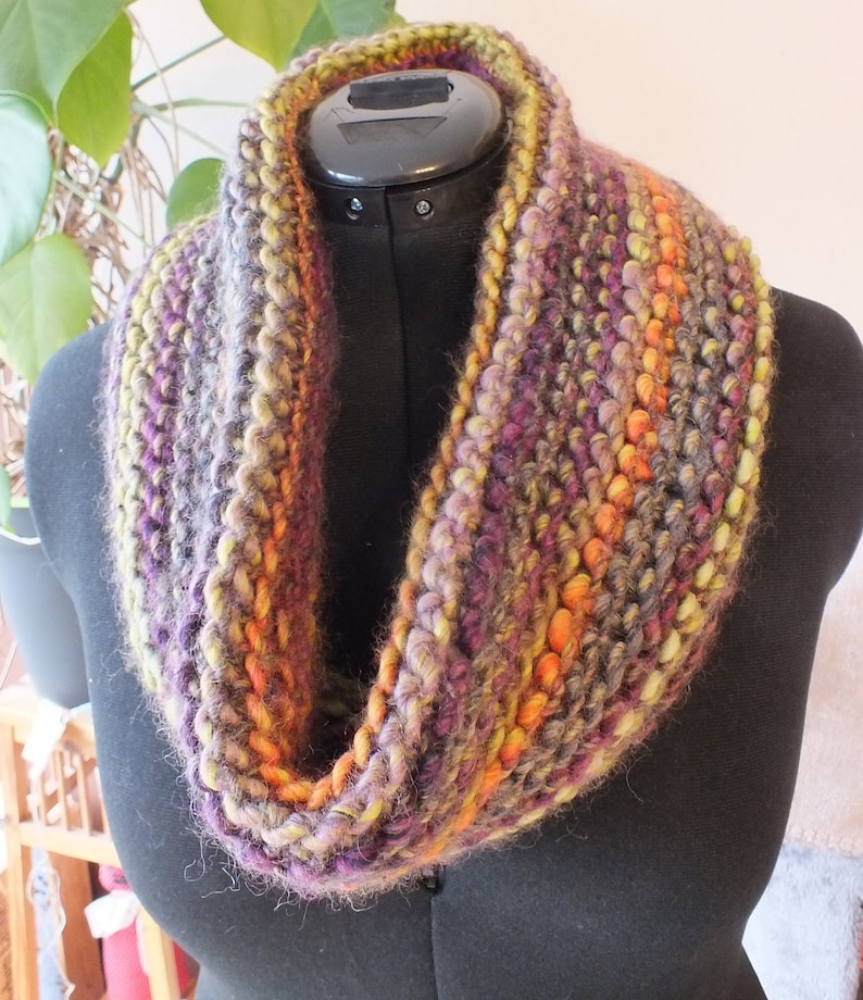 May include: A colorful crocheted infinity scarf with shades of purple, orange, and green.