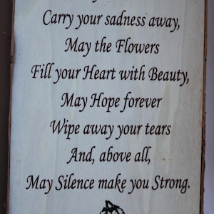 May include: Wooden plaque with a light background and dark brown text. The text reads "May the Stars Carry your sadness away... May Silence make you Strong." Two black feathers are at the bottom.