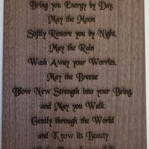 May include: A wooden plaque with a poem engraved in a cursive font. The poem reads: "May the Sun Bring you Energy by Day, May the Moon Sofily Restore you by Night, May the Rain Wash Away your Worries, May the Breeze Blow New Strength into your Being, and May you Walk Gently through the World and Know its Beauty All the Days of your Life."