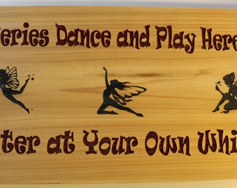 May include: Wooden sign with the text "Fairies Dance and Play Here... Enter at Your Own Whim!" in a burgundy font. The sign features three black silhouettes of fairies with wings.