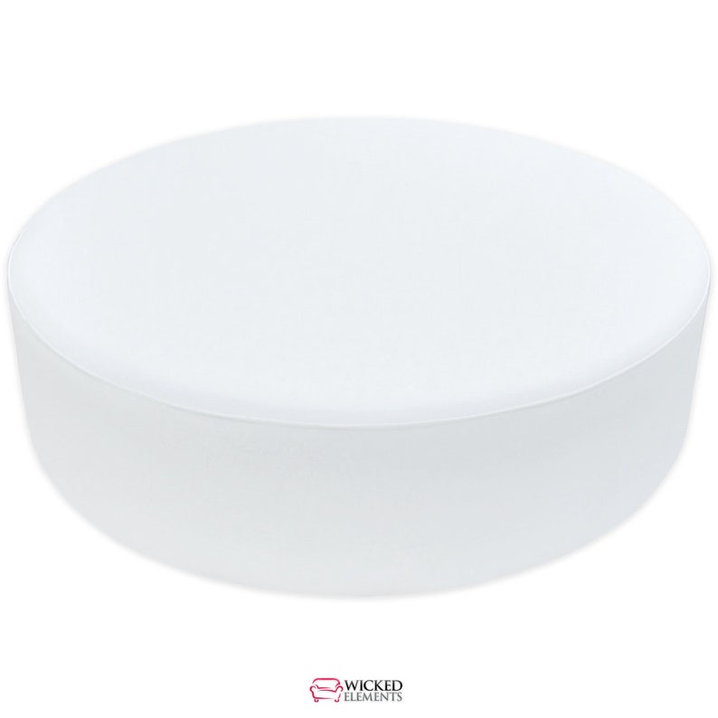 A large, round, upholstered ottoman bench with a smooth, flat top, designed as a centerpiece or additional seating. The ottoman is shown in a sleek, white leatherette fabric and rests on small, discreet feet. It measures approximately 54 inches in diameter and 17 inches in height.