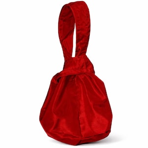 Peut inclure: Un sac rouge en velours avec cordon de serrage et une poignée assortie. Le sac a un fond arrondi et un haut froncé, créant une forme douce et élégante. La poignée est une boucle, parfaite pour porter ou suspendre.