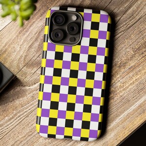 May include: A phone case with a checkered pattern in black, white, yellow, and purple.