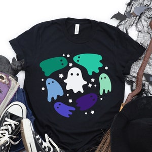 May include: Black t-shirt featuring a design of white and multi-coloured ghosts in a circle. The ghosts are in shades of green, blue, and purple.