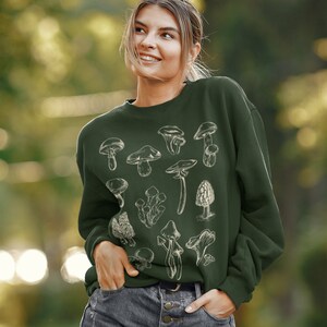 May include: A dark green sweatshirt with a white graphic print of various mushrooms. The sweatshirt has a crew neck and long sleeves.