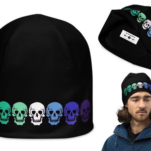 May include: Black beanie with a row of colorful skull graphics. The skulls are in a gradient of green, blue, and purple. The beanie has a white tag with the text "One Front Street" on it.