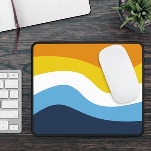 May include: A blue, yellow, white, and orange mouse pad with a wavy design. A white computer mouse is on the mouse pad.