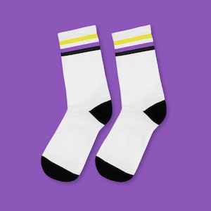 May include: A pair of white socks with black heels and toes. The socks have a yellow, purple, and black stripe pattern near the top.