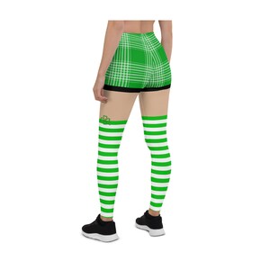 May include: Green and white plaid leggings with a shamrock design. The leggings have a high waist and are made of a stretchy material.