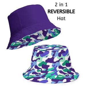 May include: Two-in-one reversible bucket hat. One side is solid purple, the other features a camouflage pattern in shades of blue, green, and white. The text "2 in 1 REVERSIBLE Hat" is displayed in black.