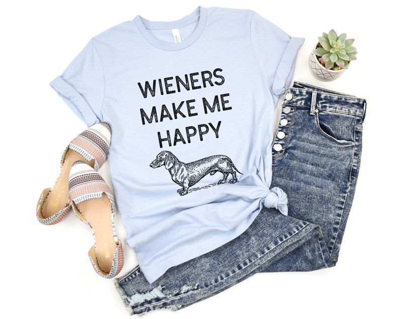 Puede incluir: Una camiseta azul claro con el texto "Wieners Make Me Happy" y una ilustraci&oacute;n en blanco y negro de un dachshund.