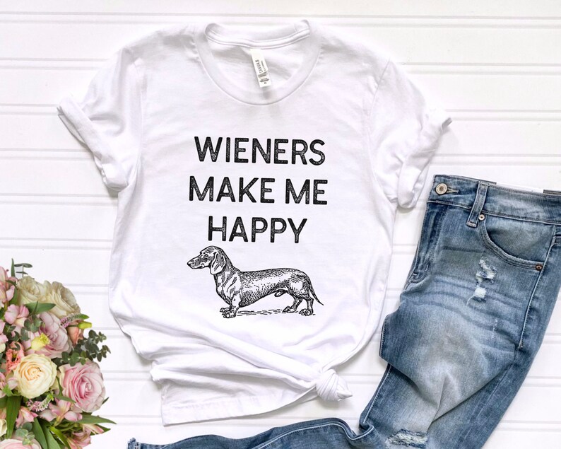 Puede incluir: Camiseta blanca con texto negro que dice "Wieners Make Me Happy" y una ilustraci&oacute;n en blanco y negro de un dachshund.