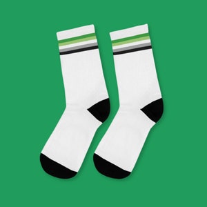 May include: A pair of white socks with black heels and toes. The socks have a green, black, and white stripe pattern near the top.