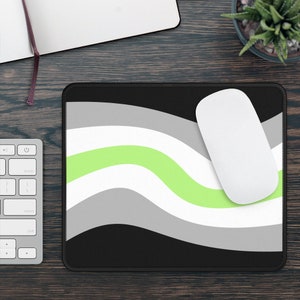 May include: A black, green, white and grey mouse mat with a wavy design. The mouse mat has a stitched edge.