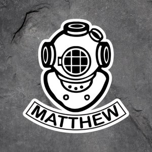 May include: Black and white sticker of a diving helmet with the name "MATTHEW" written on a banner underneath.