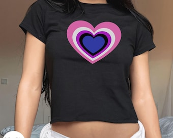 Puede incluir: Una camiseta negra recortada con un diseño de corazón rosa, morado y azul. El corazón tiene varias capas y está centrado en la camiseta.
