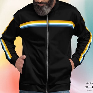 May include: Black zippered jacket with colorful horizontal stripes across the chest and down the sleeves. The jacket has a stand-up collar and two pockets.