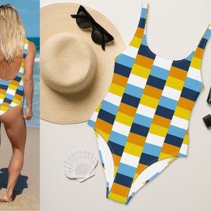 May include: A one-piece swimsuit with a geometric pattern in shades of blue, yellow, and white. The swimsuit has a scoop neck and a low back.