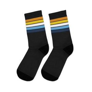 May include: A pair of black socks with colorful stripes. The stripes are yellow, white, light blue, and dark blue.