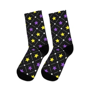 May include: A pair of black socks with a pattern of yellow and purple stars on a black background. The stars are outlined in white and connected by white dashed lines.