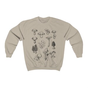 May include: A beige sweatshirt with a black and white illustration of various types of mushrooms.