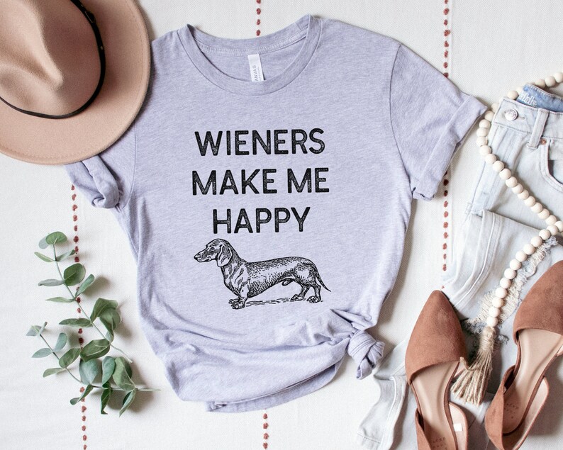 Puede incluir: Una camiseta gris con el texto "Wieners Make Me Happy" y una ilustraci&oacute;n en blanco y negro de un dachshund.
