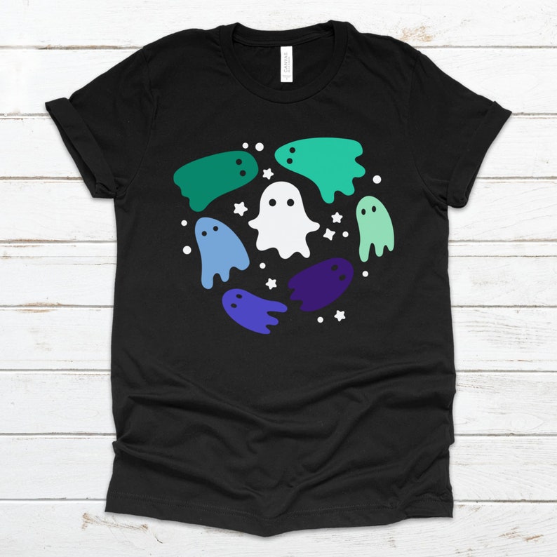 May include: Black t-shirt featuring a design of white and multi-coloured ghosts in a circle. The ghosts are in shades of green, blue, and purple.